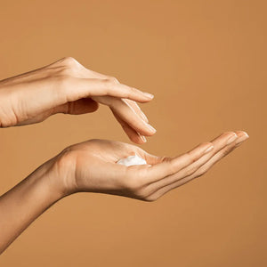 woman's hands applying organic non toxic body lotion for dry skin with neutral background