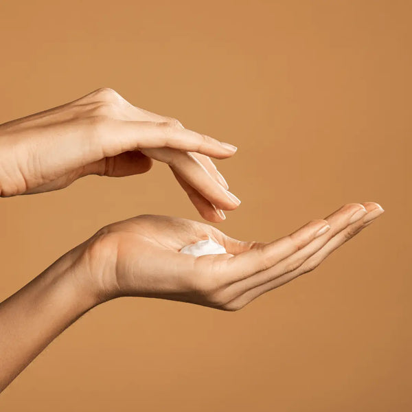 Hands applying body lotion to dry skin
